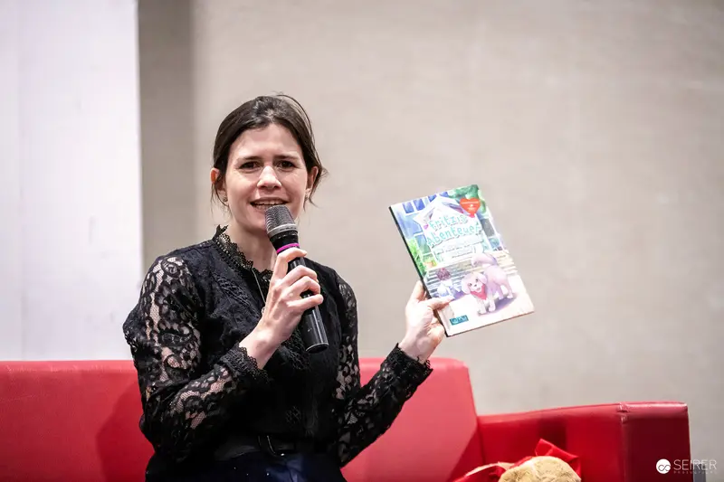 Book Presentation at Vienna Event with Woman in Black Lace Holding Microphone and Publication