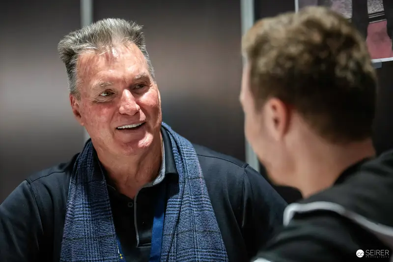 Smiling Gentleman in Blue Scarf at Intimate Conversation During Event