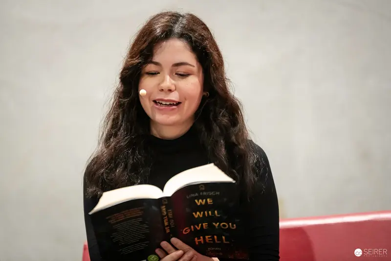 Woman Reading Provocative Book with Joyful Expression at Event