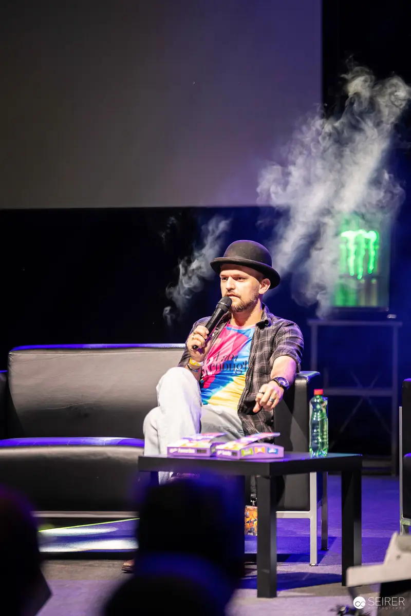 Panel speaker in bowler hat on stage sofa at VIECC Vienna Comic Con 2023
