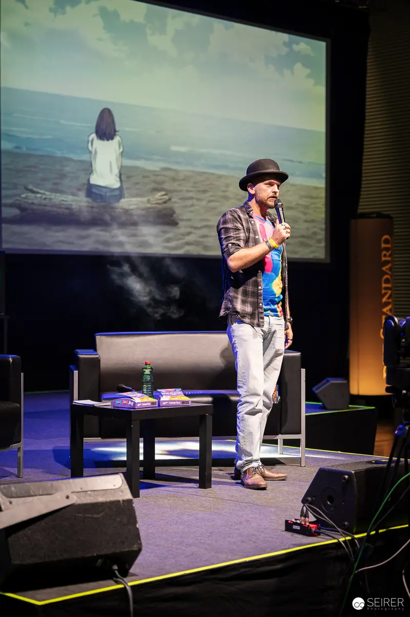 Panel host in bowler hat speaking on stage at VIECC Vienna Comic Con 2023