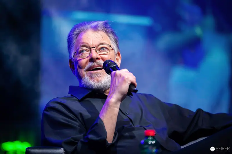 Grey-bearded panel guest speaking into handheld microphone at VIECC Vienna Comic Con 2023