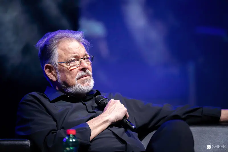 Grey-bearded panel guest with microphone on stage at VIECC Vienna Comic Con 2023