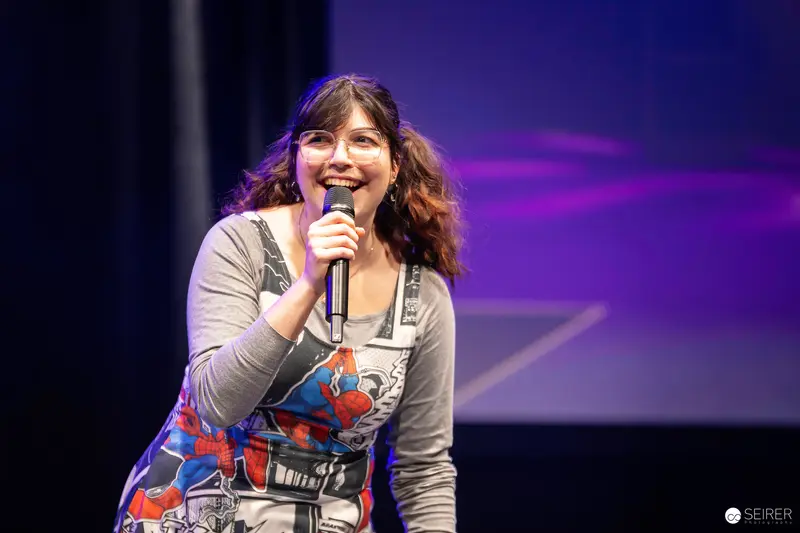 Panel host with handheld microphone on stage at VIECC Vienna Comic Con 2023