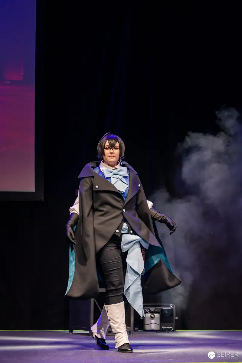 Cosplayer in Black Coat and Blue Bow Tie on VIECC Vienna Comic Con Stage