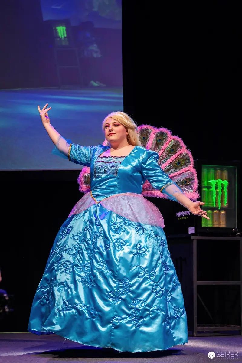 Cosplayer in Blue Satin Ball Gown with Peacock Feather Wings on VIECC Stage