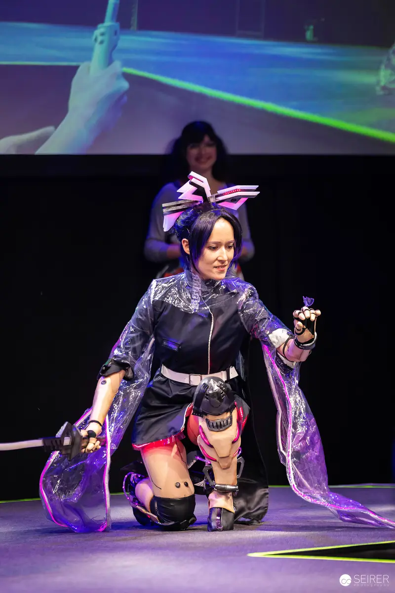 Cyberpunk cosplayer kneels with katana on the VIECC Vienna Comic Con stage, November 2023