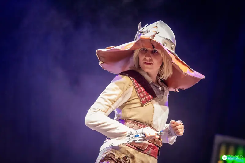 Cosplayer in wide-brimmed helmet and patchwork tunic on stage at VIECC Vienna Comic Con 2023