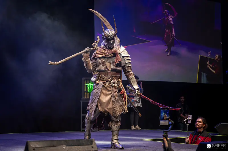 Horned samurai-style cosplayer with staff and sword on VIECC Vienna Comic Con stage