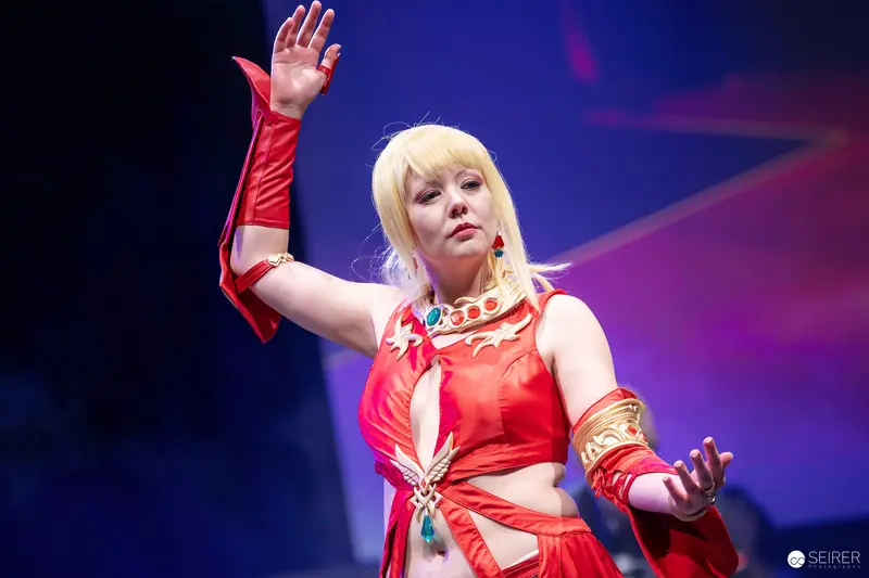 Cosplayer in Red Costume with Gold Collar Poses on Stage at VIECC Vienna Comic Con 2023
