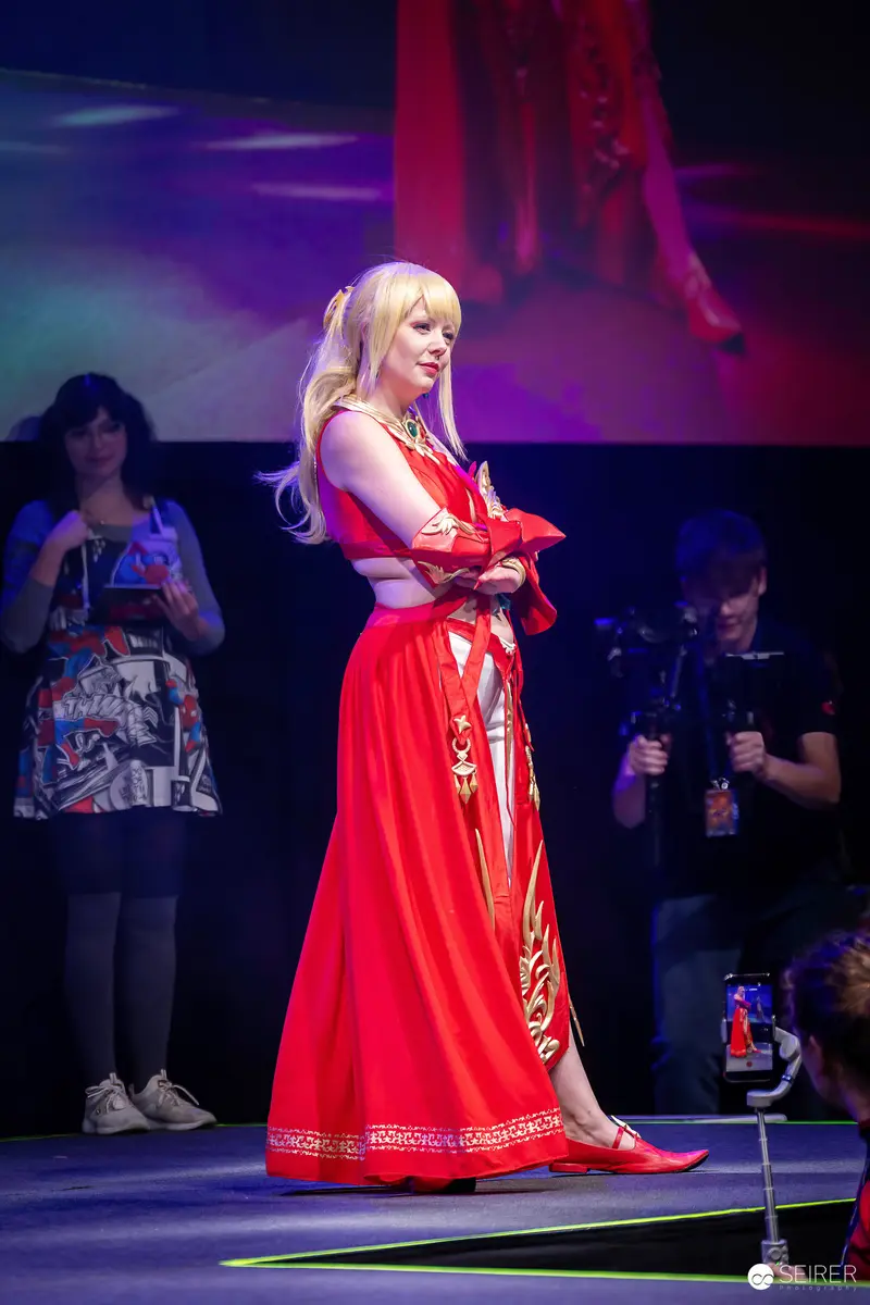 Blonde Cosplayer in Red and Gold Gown on Stage at VIECC Vienna Comic Con 2023
