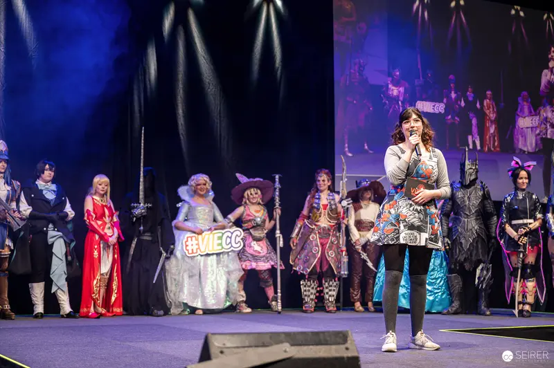 Cosplay contest host with microphone addresses lined-up contestants on VIECC Vienna Comic Con stage