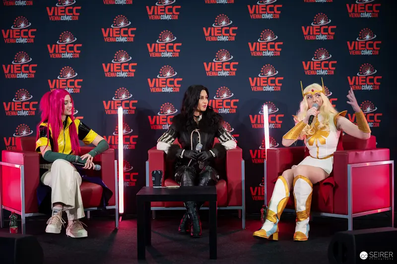 Three cosplayers on VIECC Vienna Comic Con panel stage, November 2023