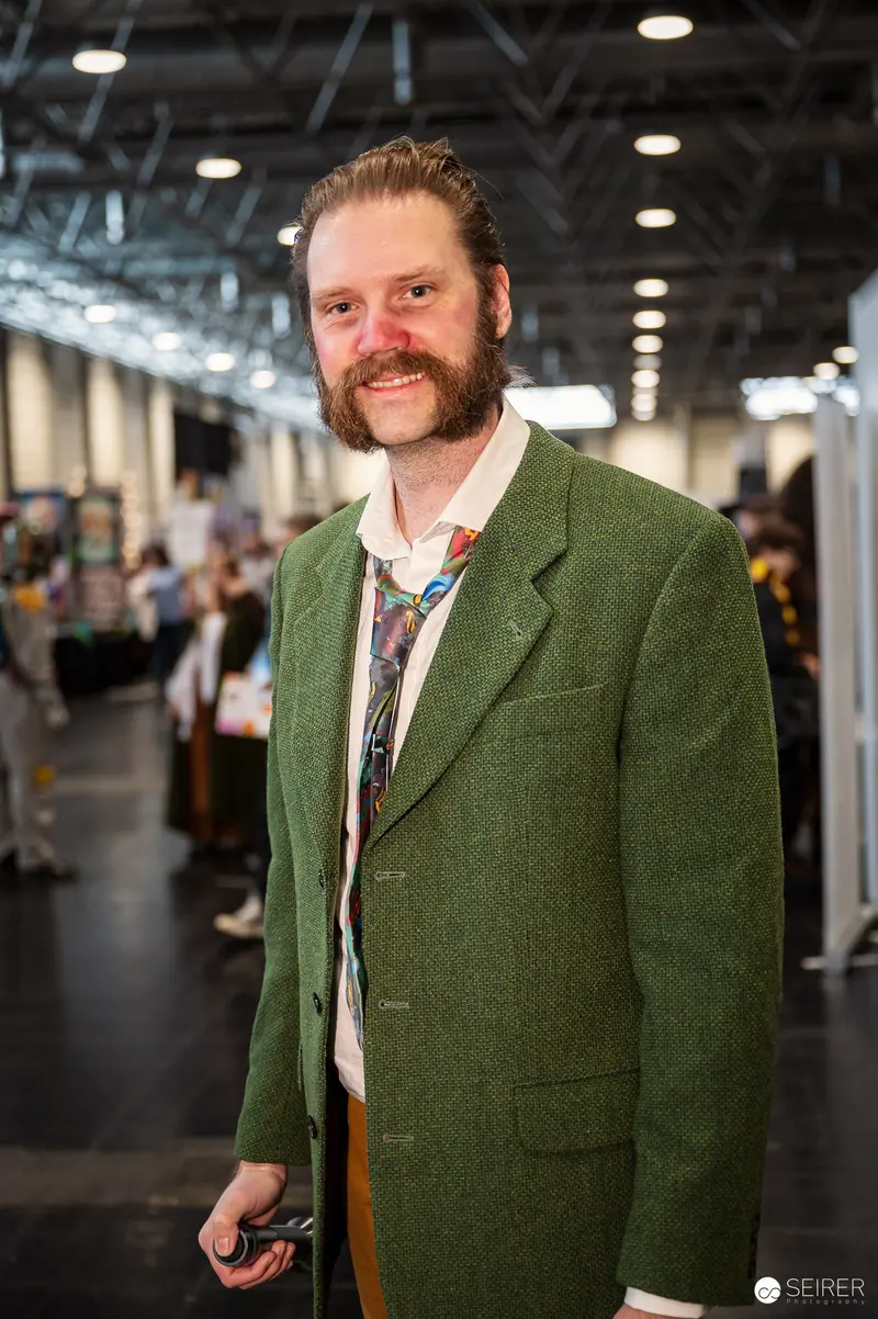 Bearded Attendee in Green Tweed Jacket and Patterned Tie at VIECC Vienna Comic Con 2023