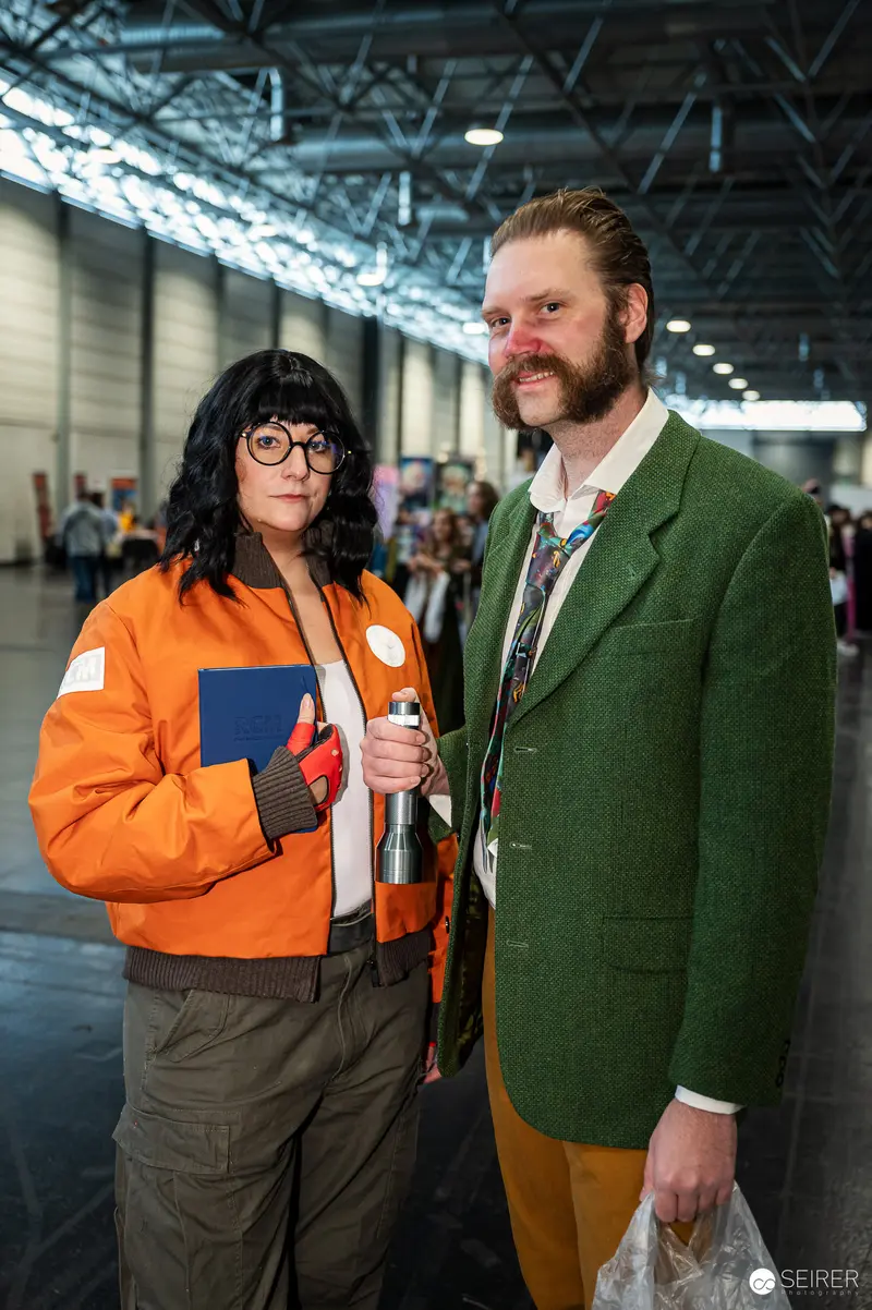 Two cosplayers in orange bomber jacket and green tweed blazer at VIECC Vienna Comic Con 2023