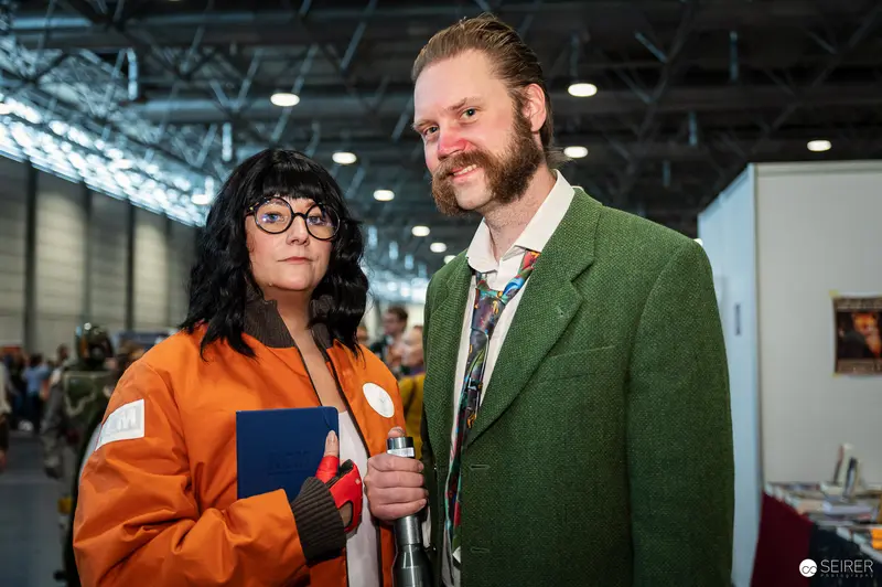 Cosplay Duo in Orange Flight Jacket and Green Tweed Suit at Vienna ComicCon 2023