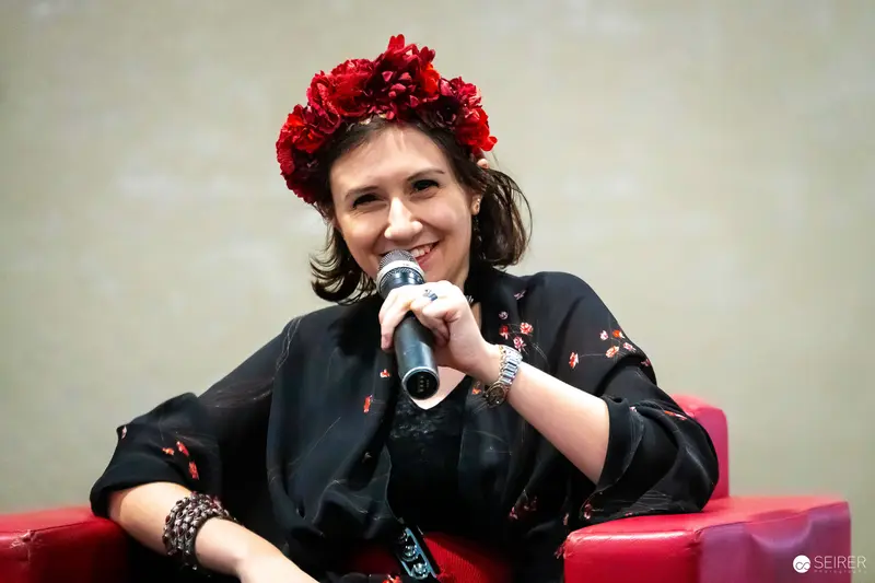 Panel speaker in red flower crown with microphone at VIECC Vienna Comic Con 2023