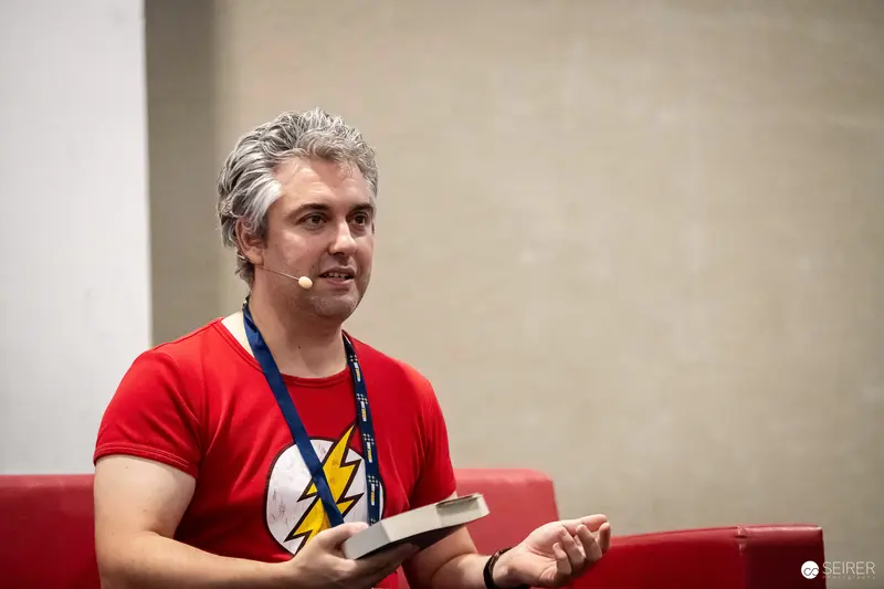 Panel speaker in Flash T-shirt holding book at VIECC Vienna Comic Con 2023