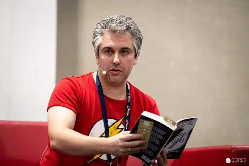Author reading German-language space opera novel on panel stage at VIECC Vienna Comic Con 2023