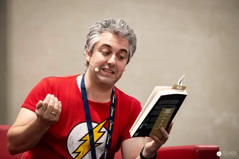 Author reads from Pan Verlag paperback wearing Flash T-shirt at VIECC Vienna Comic Con 2023