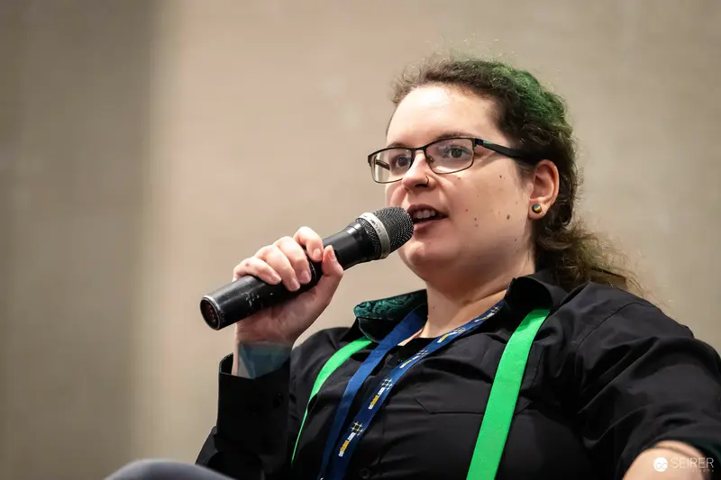 Panel speaker with handheld microphone and green lanyard at VIECC Vienna Comic Con 2023