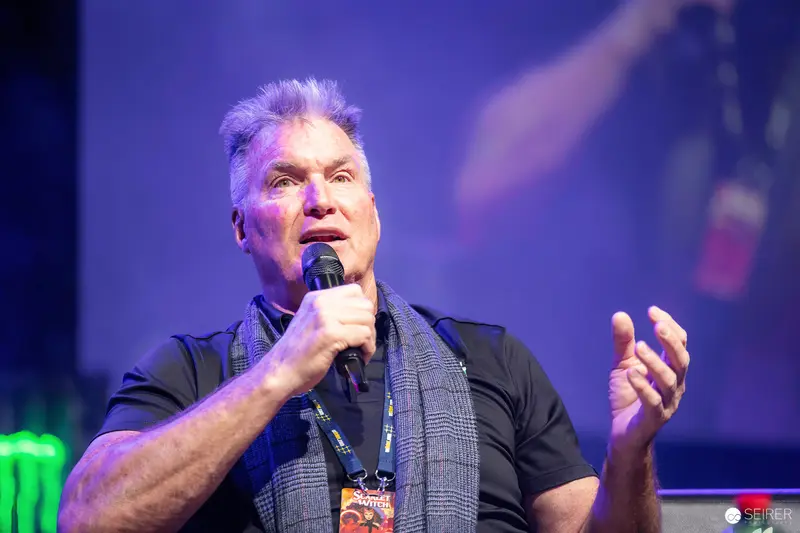 Grey-haired panel guest speaking into handheld microphone at VIECC Vienna Comic Con 2023