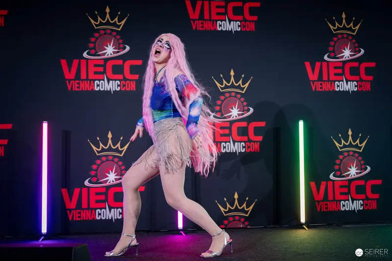 Drag performer with pink hair on VIECC Vienna Comic Con stage, November 2023