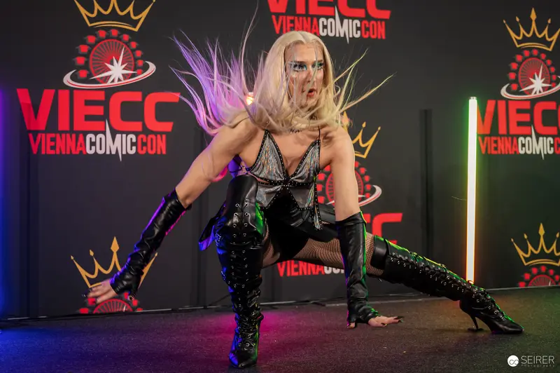 Cosplayer in crouching pose with thigh-high boots on VIECC Vienna Comic Con stage