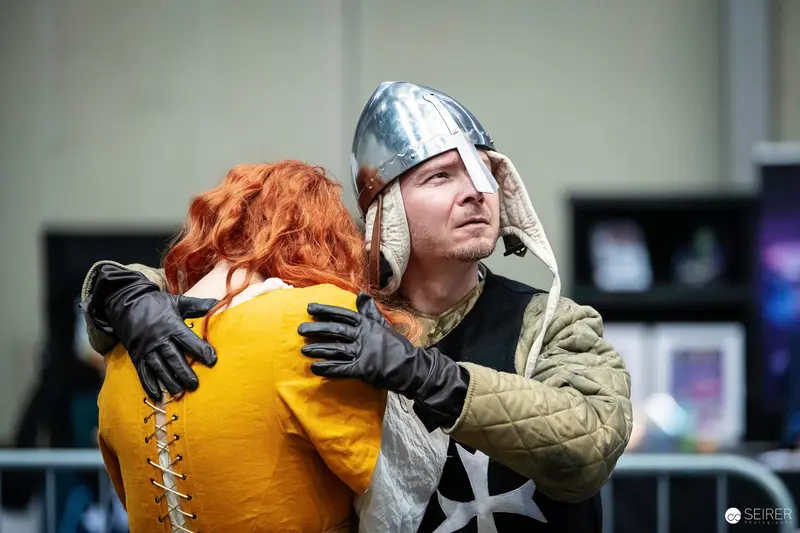 Medieval Knight Cosplayer Embracing Red-Haired Cosplayer at VIECC Vienna Comic Con 2023