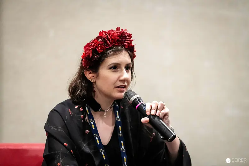 Panel speaker in red floral crown with microphone at VIECC Vienna Comic Con 2023