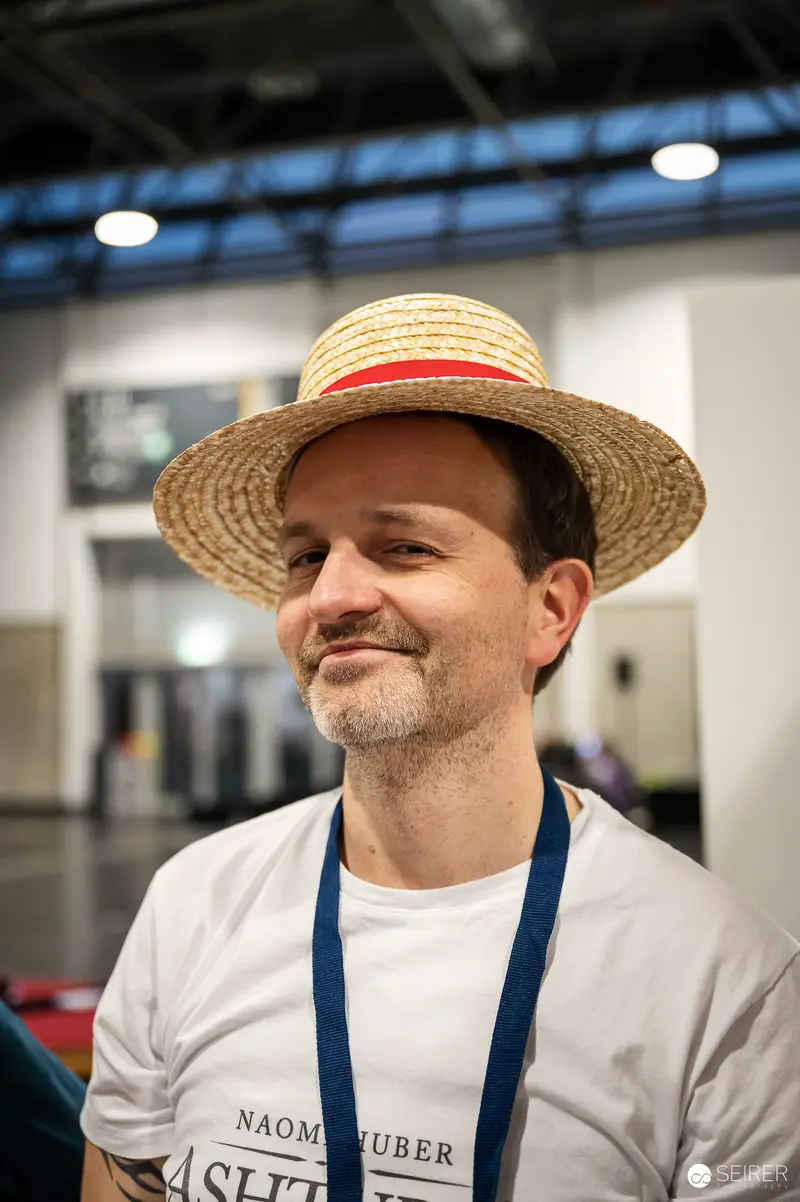 Attendee in straw boater hat and Naomi Huber shirt at VIECC Vienna Comic Con 2023
