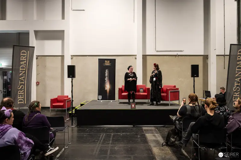 Two Speakers in Black on the PAN Literature Stage at VIECC Vienna Comic Con 2023