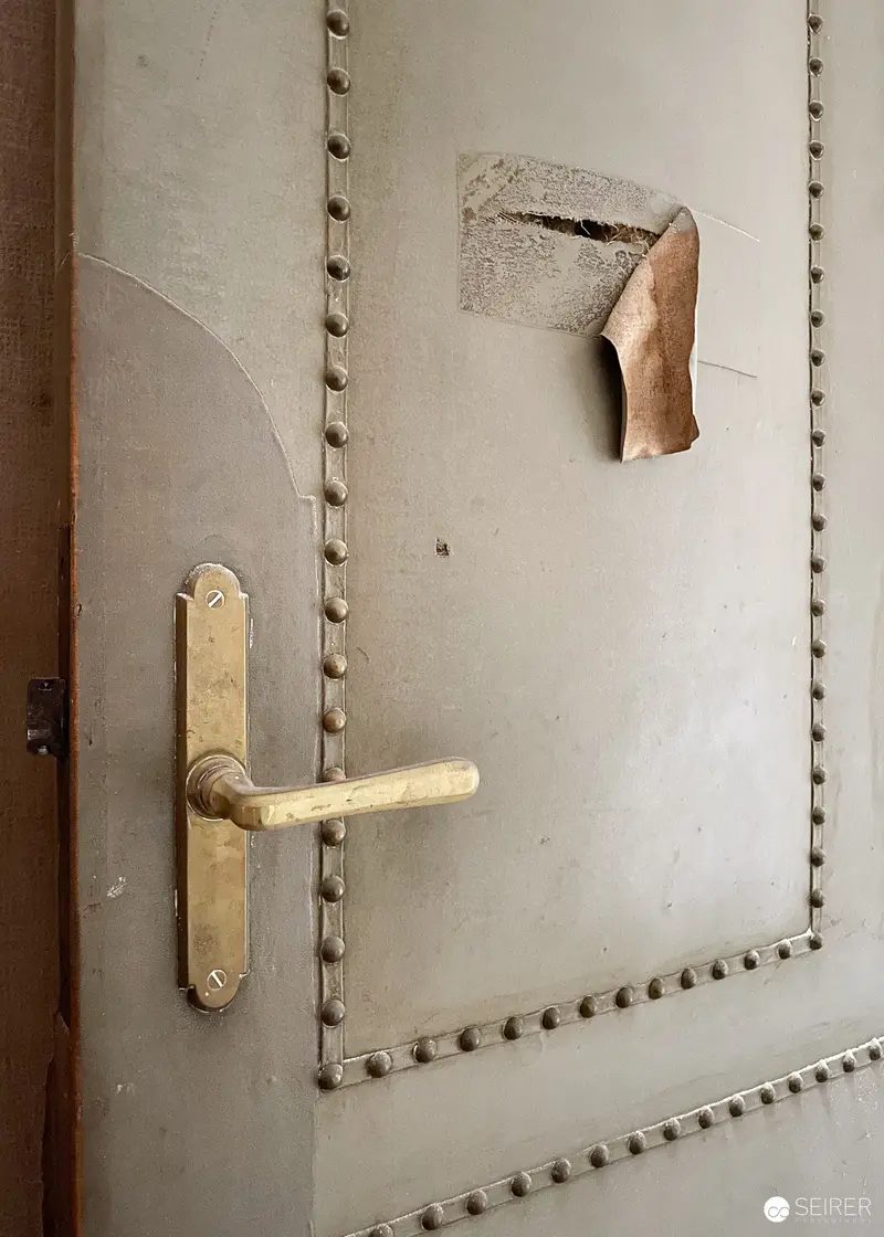 Padded Door with Brass Handle and Torn Leather at Südbahnhotel Semmering