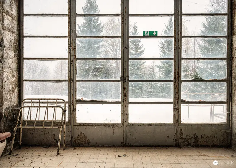 Disused metal bed frame beside snow-framed window wall, Südbahnhotel Semmering, November 2023