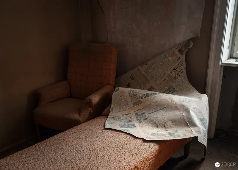 Abandoned armchair and bench beneath peeling wallpaper, Südbahnhotel Semmering, November 2023