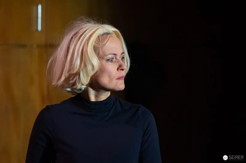 Blonde Woman in Black Turtleneck Looking Contemplatively Offstage