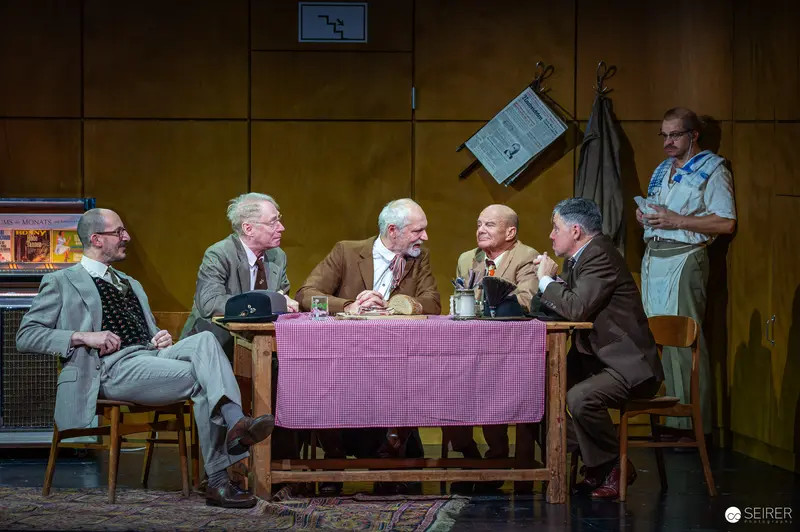 Der Himbeerpflücker Stage Performance: Men Gathered at Table in Tense Meeting