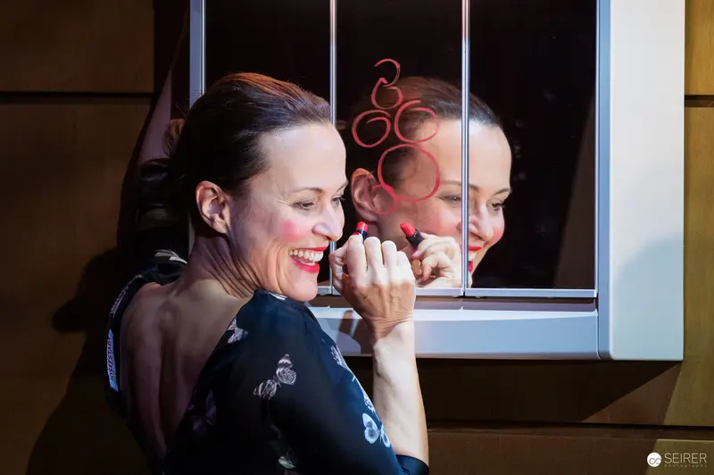 Laughing Performer Reflects in Window During Theater Production