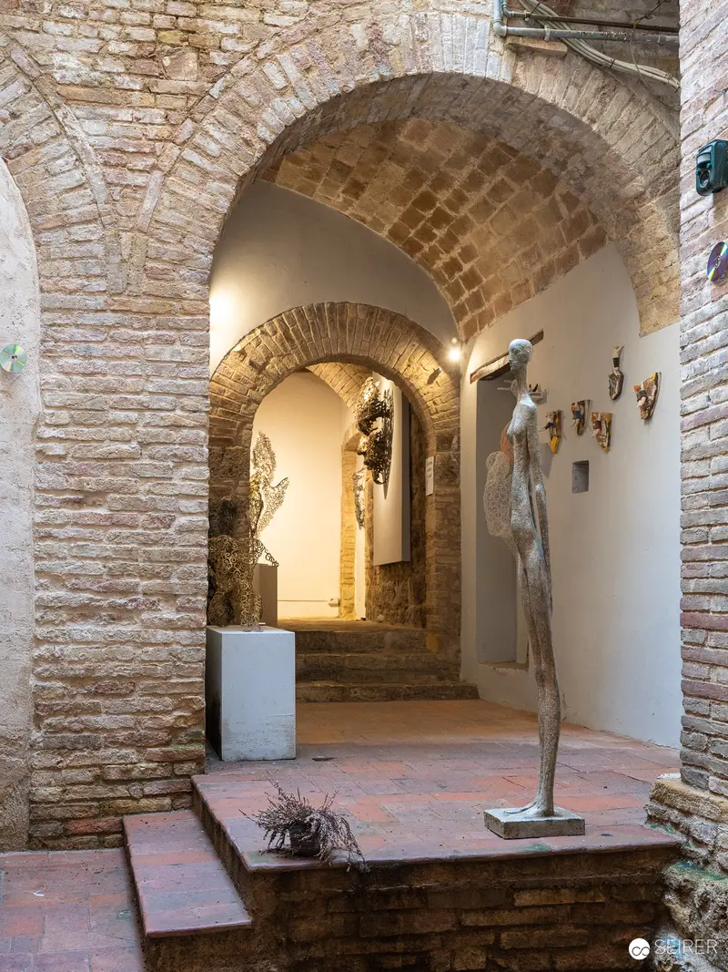 Stone Archways and Sculptural Figures in San Gimignano Gallery Interior