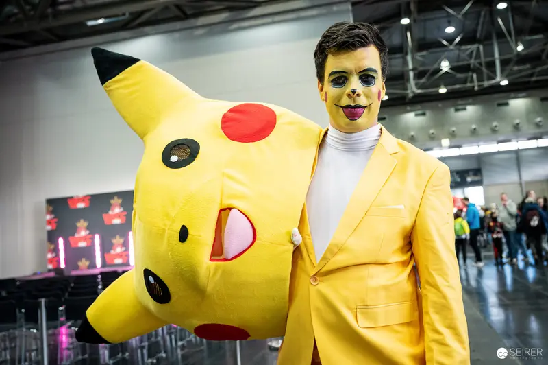 Cosplayer in Yellow Suit Poses with Pikachu at Vienna ComicCon 2023