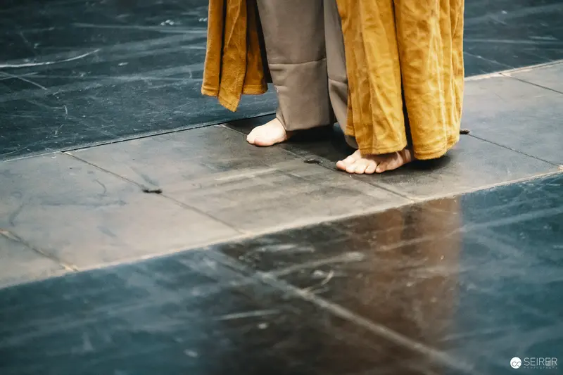 Barefoot Performers in Yellow and Beige Standing on Dark Floor
