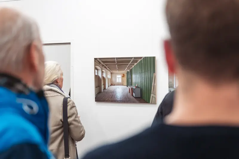 Art Gallery Visitors Examining Minimalist Interior Photograph at Prague Photo School Exhibition