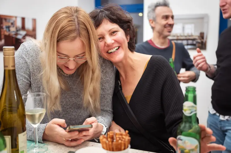 Friends Socializing at Wine Tasting Event with Smartphone and Laughter