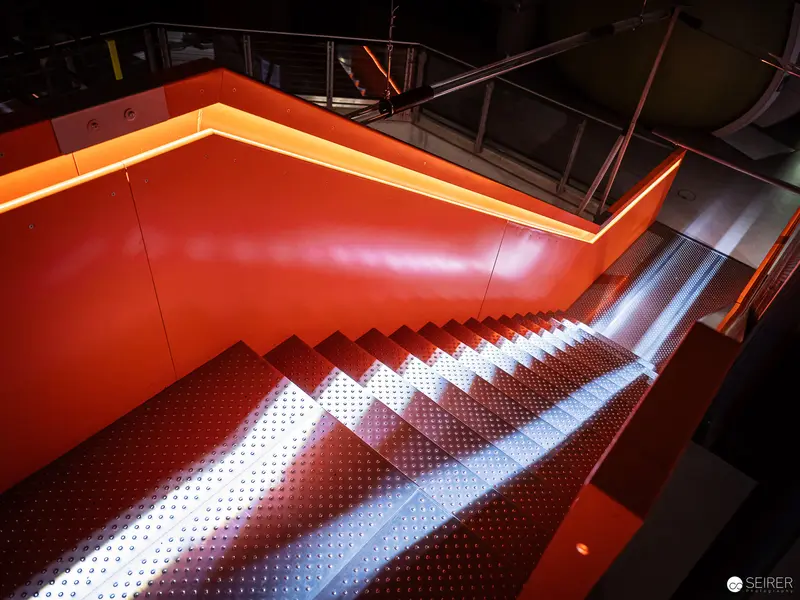 Illuminated Red Staircase with Textured Metal Steps in Modern Interior