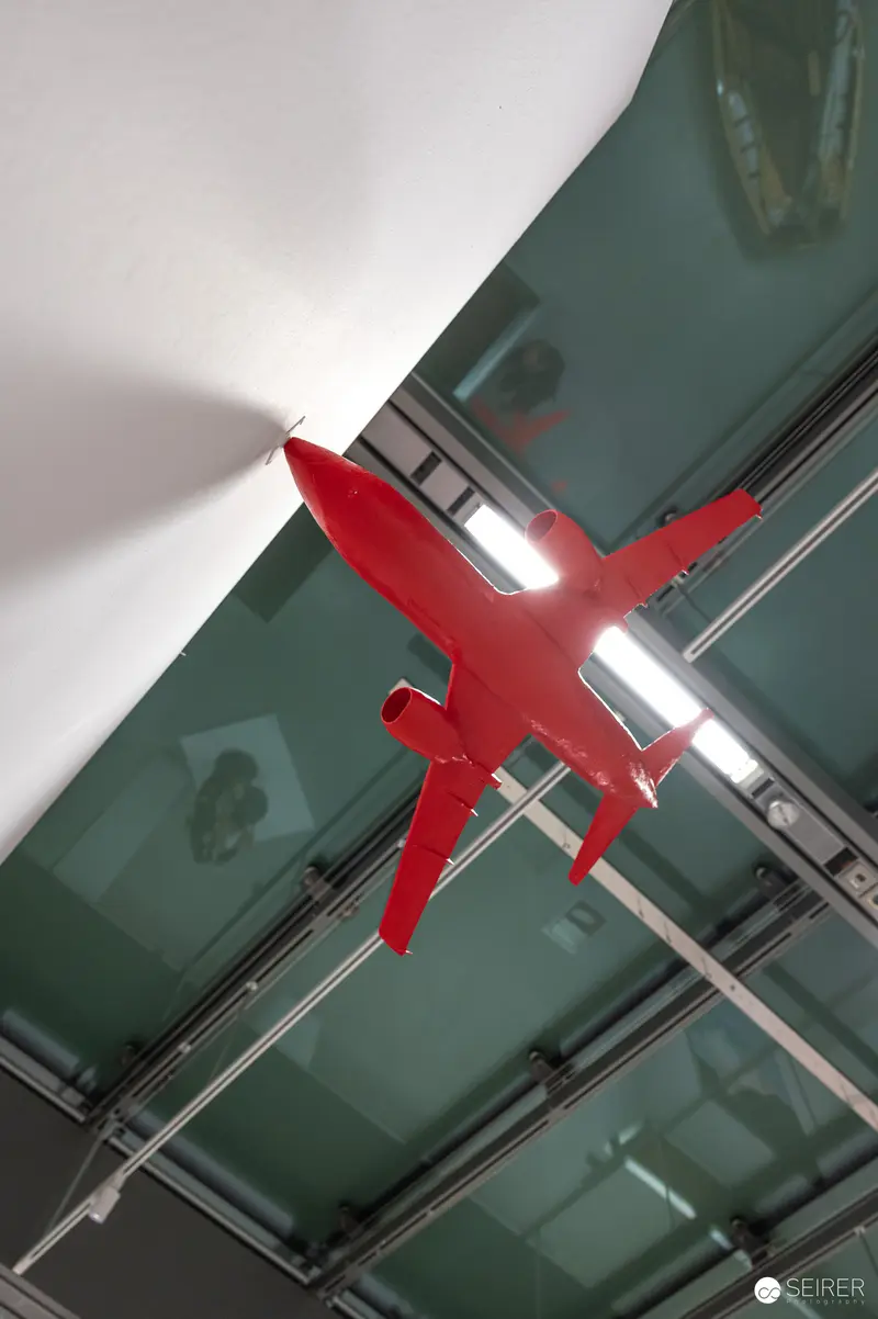 Red Aircraft Silhouette Suspended in Modern Glass Architectural Interior