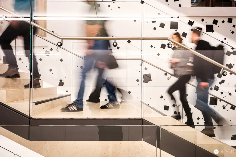 Blurred Motion on Glass-Lined Staircase with Scattered Black Squares