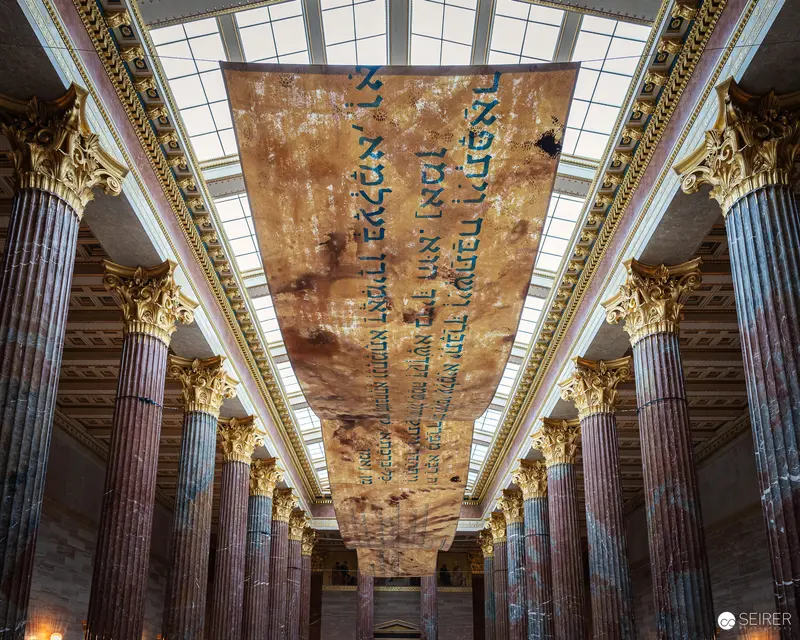 Ornate Austrian Parliament Hall with Hebrew Text Hanging from Skylit Ceiling