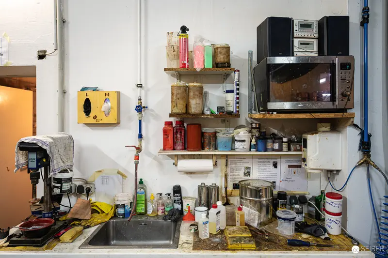 Cluttered Workshop Interior with Microwave, Sink, and Industrial Shelving