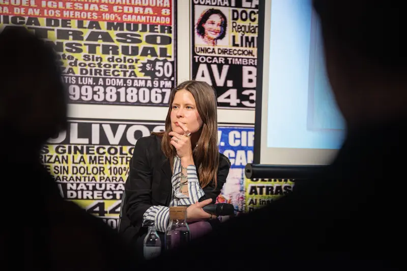 Press Conference with Woman Speaking at Media Event with Posters Behind Her