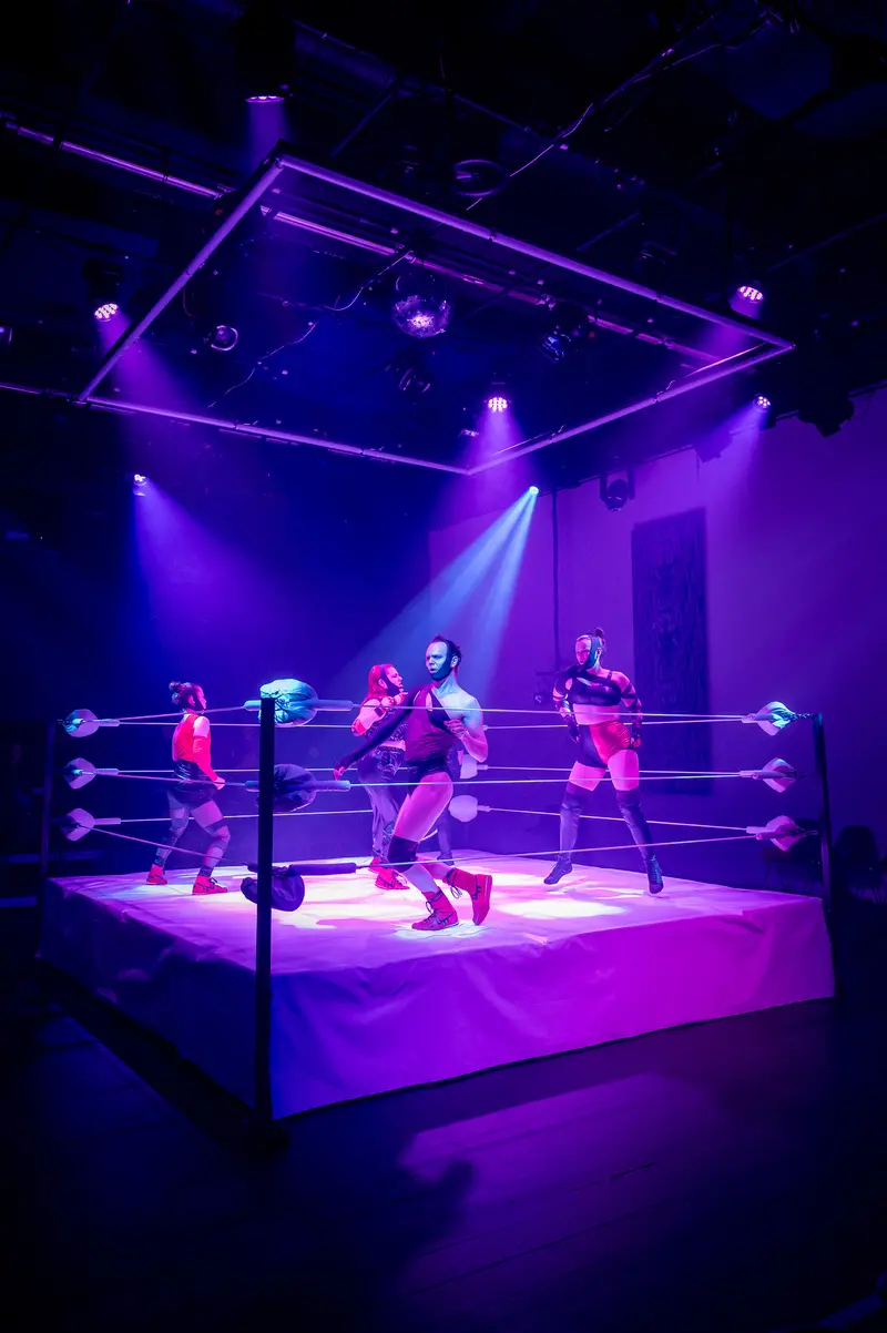 Performers in Purple-Lit Wrestling Ring at Kosmos Theater Performance
